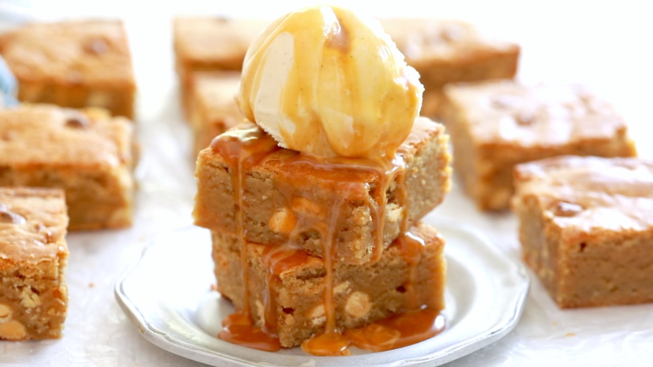 Two blondies stacked on top of each other with ice cream and caramel on top.