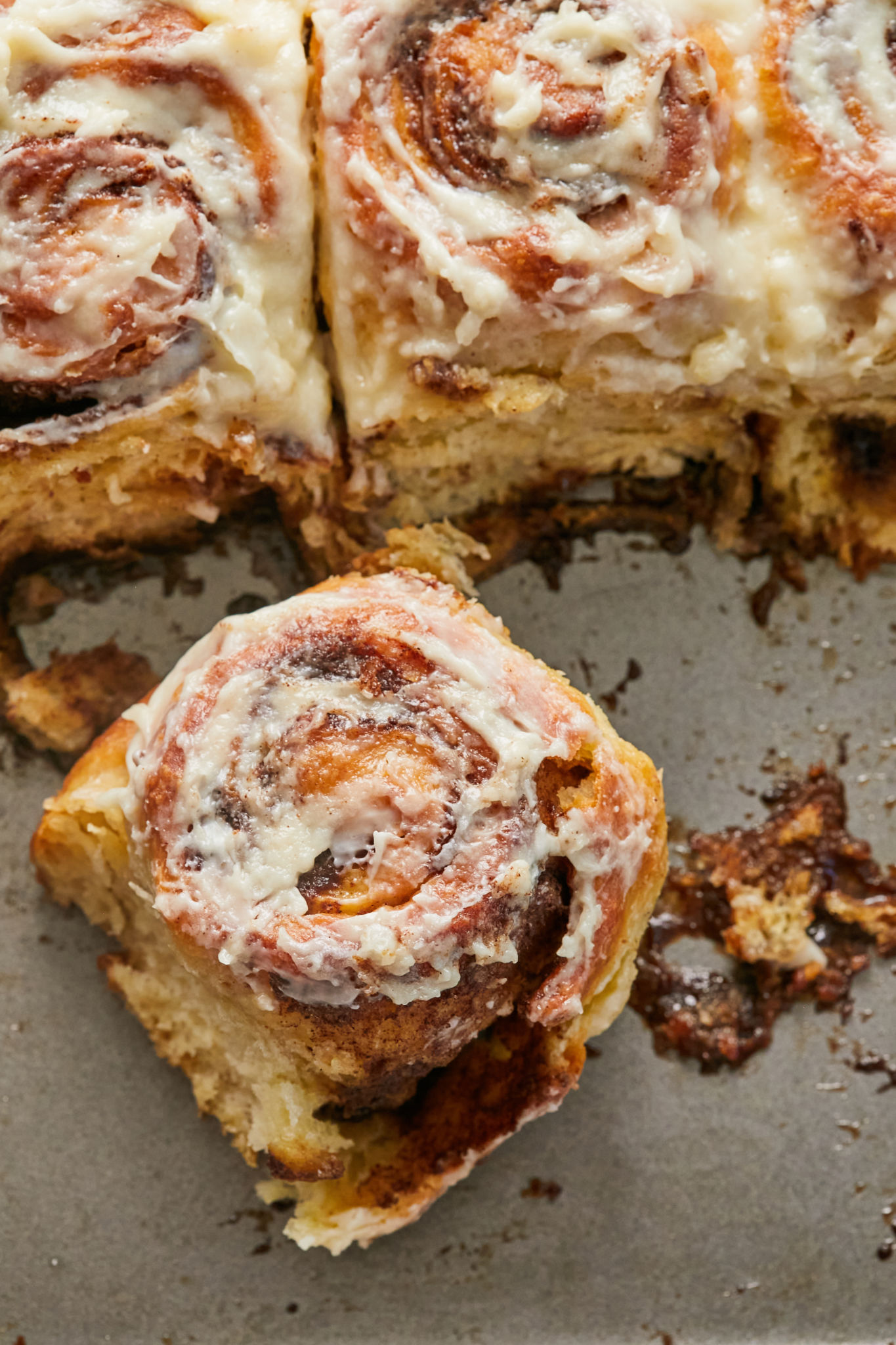 Gooey cinnamon rolls in a pan after baking and icing.