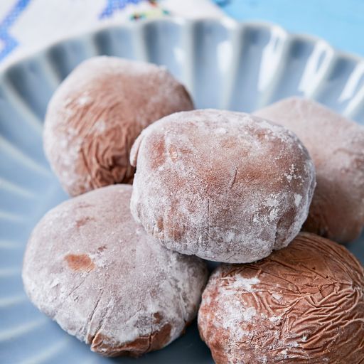 Five bite-size indulgent frozen dessert balls are placed on a blue scalloped plate and ready to serve. 