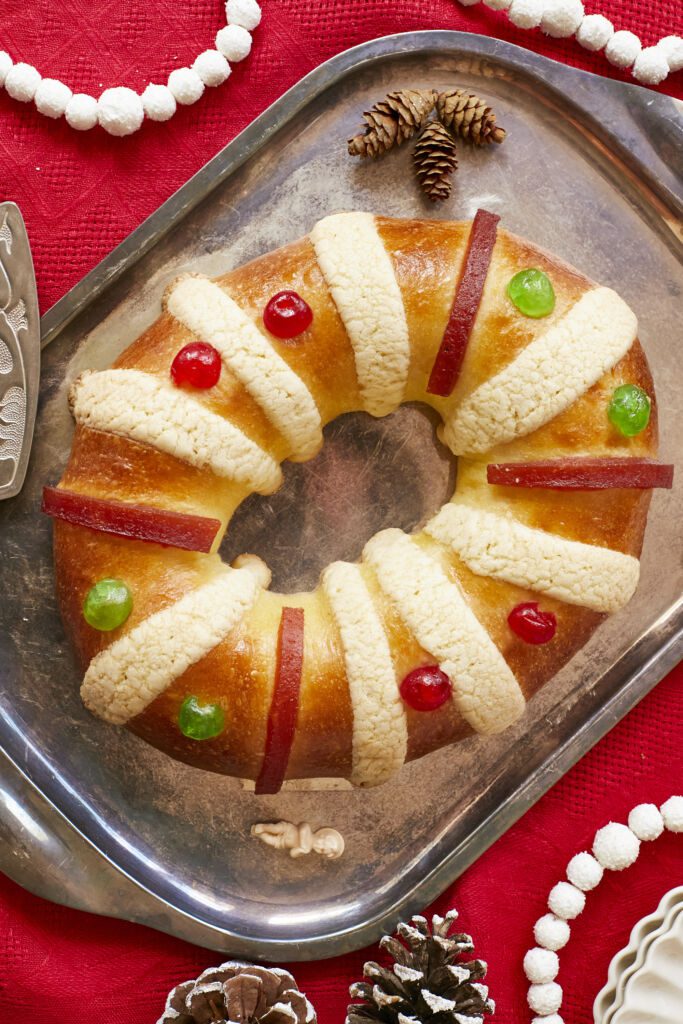 Rosca de Reyes (Three Kings Bread)is baked until golden brown. It's infusxed with orange zest and decorated with festive candied cherries, strips of quince paste, and sugar paste.